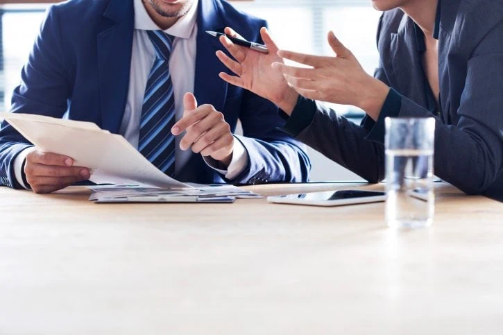 Business conversation about documents between man and women both in suits. Faces not visible.