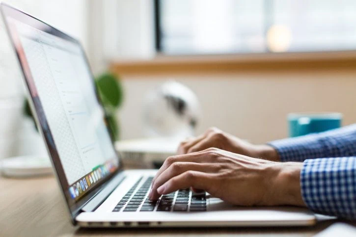 Person typing something into a laptop at the desk